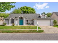 Charming single-story home with a well-manicured lawn, gray roof, and light gray stucco at 1004 Moccasin Run Rd, Oviedo, FL 32765