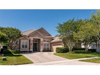 Charming beige single-story home with a tile roof, a brick driveway and mature landscaping at 1027 Algare Loop, Windermere, FL 34786