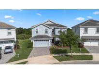 Charming two-story home with a two-car garage, lush landscaping, and a brick driveway at 1571 Palmero Way, Davenport, FL 33896
