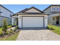 Charming home with a white garage door and an inviting paver driveway and walkway at 1900 Archer Dr, Minneola, FL 34715