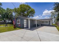 Charming gray home featuring a spacious driveway, well-kept lawn, and patriotic American flag waving in the breeze at 30 Sunset Cir, Lake Alfred, FL 33850