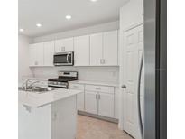 Bright kitchen features stainless steel appliances, white cabinetry, and a large island with a breakfast bar at 4721 Jasmine Cir, Leesburg, FL 34748