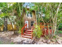Charming home exterior featuring a bright front door, wood deck, and lush, mature landscaping at 7807 Napoleon St, Orlando, FL 32825