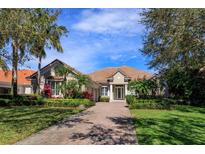 Charming one-story home with a well-manicured lawn, lush landscaping, and a brick driveway leading to the entrance at 11139 Camden Park Dr, Windermere, FL 34786