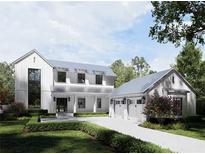 Beautiful white farmhouse with a three-car garage and brick-paved driveway surrounded by lush landscaping at 1256 Water Maple Dr, Oakland, FL 34787