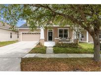 Charming beige two-story home featuring a cozy front porch and attached two-car garage at 1825 Saffron Plum Ln, Orlando, FL 32828