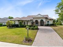 Charming single-story home with a well-manicured lawn, brick driveway, and inviting front entrance at 5509 Meadow Hill Loop, Lady Lake, FL 32159