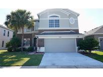 Two-story home featuring a large driveway, a 2-car garage, and a beautiful lawn with mature landscaping at 13520 Meadow Bay Loop, Orlando, FL 32824