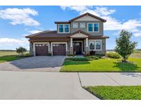 Charming two-story home with a three-car garage, manicured lawn and a beautiful brick driveway on a sunny day at 200 Valencia Ridge Dr, Auburndale, FL 33823