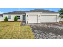Charming single-story home featuring a two-car garage and well-maintained front yard with lush greenery at 332 Blue Lake Cir, Kissimmee, FL 34758
