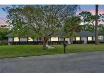 Charming single-story home with a well-manicured lawn, mature landscaping, and a brick facade at 401 Sanford Ave, Longwood, FL 32750