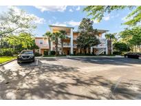 Three-story peach-colored condo with a parking lot, mature trees, and clear blue skies at 509 New Providence, Davenport, FL 33897