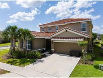 Beautiful two-story home featuring a red tile roof, attached two car garage, and well manicured lawn at 7618 Oakmoss Loop, Davenport, FL 33837
