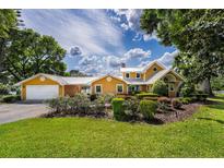 Charming two-story home with a well-manicured lawn, colorful flower beds, and attached garage at 11200 Lane Park Rd, Tavares, FL 32778