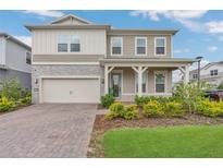 Charming two-story home featuring a stone facade, front porch, and well-maintained landscaping at 13640 Haulover Beach Ln, Orlando, FL 32827