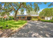 Charming brick home featuring a well-manicured lawn, mature trees, and an inviting front entrance at 1511 Crestline St, Orlando, FL 32806