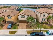 Inviting two-story home with a well-manicured lawn and brick-paved driveway, complemented by a serene lake view at 1864 Nice Ct, Kissimmee, FL 34747