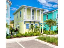 Charming two-story coastal cottage with colorful facade, white balcony, manicured landscaping, and sidewalk access at 2978 Latitude Ln, Kissimmee, FL 34747