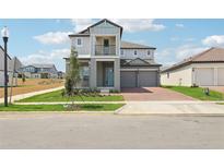 Two-story home featuring a gray exterior, balcony, brick driveway, and attached two-car garage at 5260 Citrus Leaf Blvd, Winter Garden, FL 34787