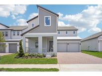Modern two-story home with a brick driveway, covered porch, metal roof and neutral-tone exterior paint at 5307 Citrus Leaf Blvd, Winter Garden, FL 34787