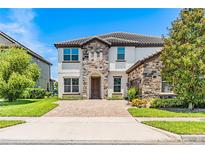 Charming two-story home featuring a stone facade, well-manicured lawn, and a paved driveway leading to the entrance at 11689 Hampstead St, Windermere, FL 34786