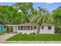 Charming single-story home featuring white brick and siding, a covered carport, and a well-manicured lawn with a palm tree at 247 S Marydell Ave, Deland, FL 32720
