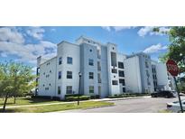 Modern condo building with neutral paint, balconies, parking lot, and lush landscaping on a sunny day at 3120 Paradox Cir # 101, Kissimmee, FL 34746