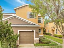 Two-story home featuring a two-car garage, tan and brown stucco, manicured landscaping, and lovely curb appeal at 3166 Rodrick Cir, Orlando, FL 32824