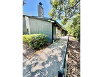 Exterior view of the home featuring a walkway, gray siding, and a chimney at 238 Riverbend Dr # 105, Altamonte Springs, FL 32714