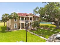 Stunning two-story building with a red tile roof and multiple balconies overlooking lush green spaces at 2808 Osprey Cove Pl # 201, Kissimmee, FL 34746