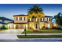 Stunning two-story home with a three-car garage, mature landscaping, and inviting curb appeal at twilight at 427 Egret Place Dr, Winter Garden, FL 34787