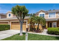 A beautifully landscaped townhome featuring a two-car garage, mature trees, and a well-manicured lawn at 484 Harbor Winds Ct, Winter Springs, FL 32708