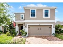 Two-story home with brick driveway, attached garage and manicured landscaping at 812 Marcel Loop, Davenport, FL 33837