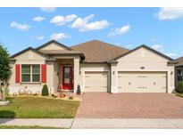 Charming single-story home featuring a manicured lawn, brick driveway, and a two-car garage at 1199 Playa Del Sol Ln, St Cloud, FL 34771