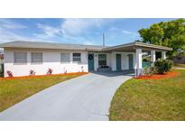 Charming home with a covered entry, long driveway, and nicely landscaped yard with colorful plantings at 1831 Aaron Ave, Orlando, FL 32811