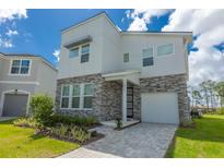 Contemporary two-story home boasting a stone facade, covered entryway, and a well-manicured front yard at 2004 Fleming Mist Pl, Kissimmee, FL 34747