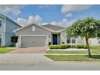 Charming single-story home with a brick driveway, manicured landscaping, and a gray stucco exterior at 299 Whirlaway Dr, Davenport, FL 33837