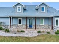 Charming blue home featuring a stone base, metal roof, and walkway leading to the inviting front door at 3550 Kaiser Ave, St Cloud, FL 34772