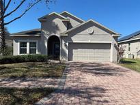 Charming single-Gathering home featuring a brick driveway and a neutral-toned stucco exterior at 457 Bridgeford Crossing Blvd, Davenport, FL 33837