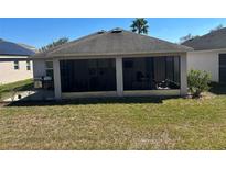 Screened-in patio with outdoor seating area, adjacent to a well-maintained yard and grill at 457 Bridgeford Crossing Blvd, Davenport, FL 33837