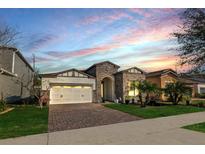 Charming single-Gathering home featuring a brick driveway, manicured lawn, and stone accents, all under a beautiful sky at 9188 Chandler Dr, Groveland, FL 34736