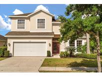 Two story home with a two car garage, manicured lawn and garden, and a red front door at 9469 Edenshire Cir, Orlando, FL 32836