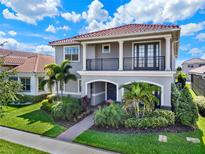 Beautiful two-story home featuring a red tile roof, balcony, and lush tropical landscaping in the front yard at 10254 Beechwood Ln, Orlando, FL 32832
