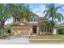 Charming two-story home featuring a well-maintained lawn, mature trees, and an attached two-car garage at 108 Portstewart Dr, Orlando, FL 32828