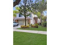 Charming two-story home features a well-manicured lawn, mature trees, and attached two-car garage at 2832 Risser Ave, Orlando, FL 32812