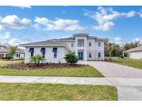 Stunning two-story home featuring a modern facade, meticulously landscaped yard, and a welcoming paver driveway at 10013 Brocksport Cir, Gotha, FL 34734