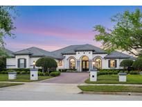 Beautiful single-story home with manicured landscaping, paver driveway, and elegant exterior lighting at 3382 Fernlake Pl, Longwood, FL 32779