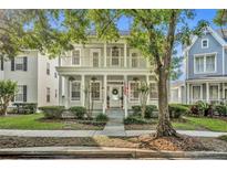 Charming two-story home with a double porch, white columns, and a well-maintained front yard at 821 Veranda Pl, Celebration, FL 34747