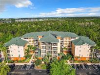 Aerial view of condo complex featuring a lush green landscape and ample parking at 9051 Treasure Trove Ln # 405, Kissimmee, FL 34747