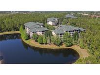 Beautiful aerial view of waterfront condo buildings surrounded by trees and overlooking a serene lake at 9061 Treasure Trove Ln # 104, Kissimmee, FL 34747